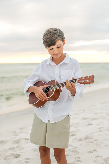 A boy plays his guitar on 30A beach for a rosemary beach photographer